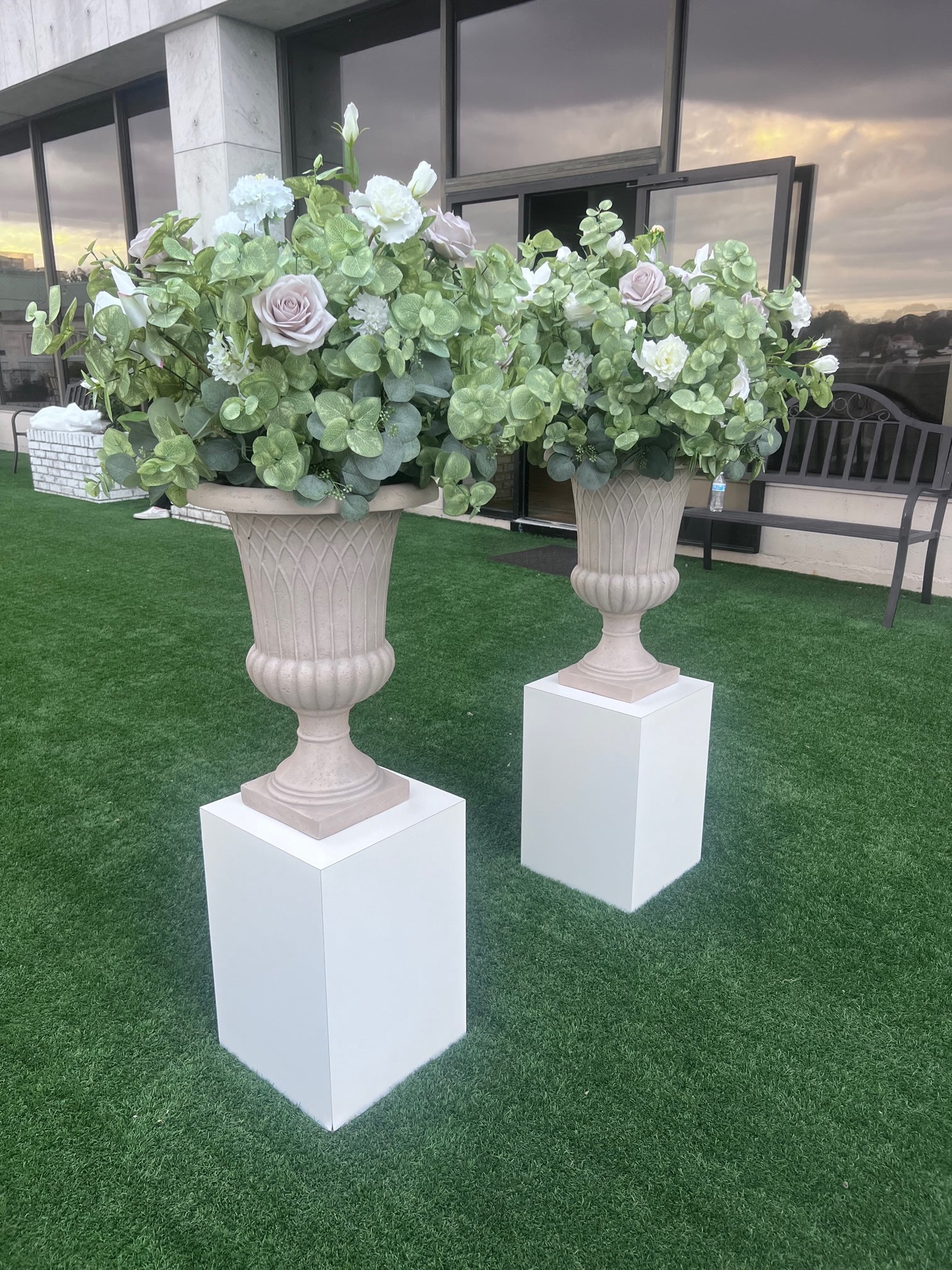 These floral urns are made with eucalyptus, taupe roses, white roses, white ranunculus, and white lisanthus. They are light and airy.