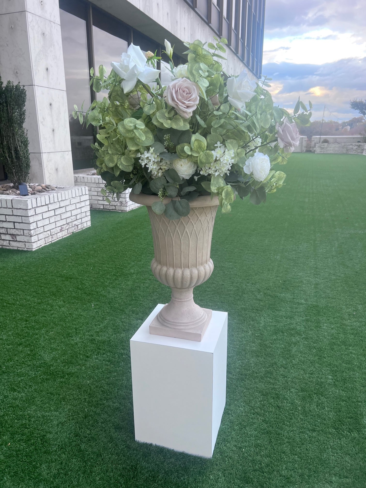 These floral urns are made with eucalyptus, taupe roses, white roses, white ranunculus, and white lisanthus. They are light and airy.