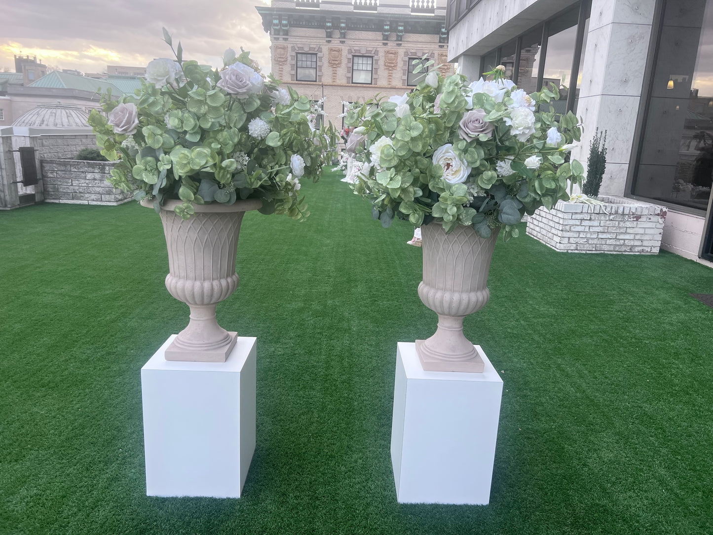 These floral urns are made with eucalyptus, taupe roses, white roses, white ranunculus, and white lisanthus. They are light and airy.