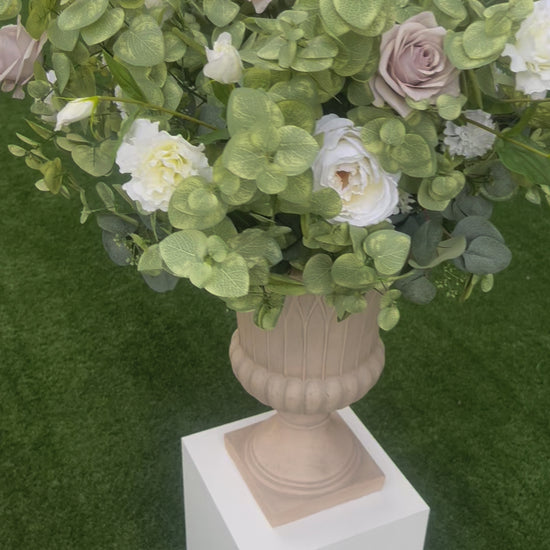 These floral urns are made with eucalyptus, taupe roses, white roses, white ranunculus, and white lisanthus. They are light and airy.