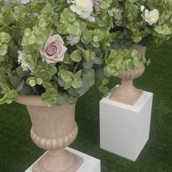 These floral urns are made with eucalyptus, taupe roses, white roses, white ranunculus, and white lisanthus. They are light and airy.