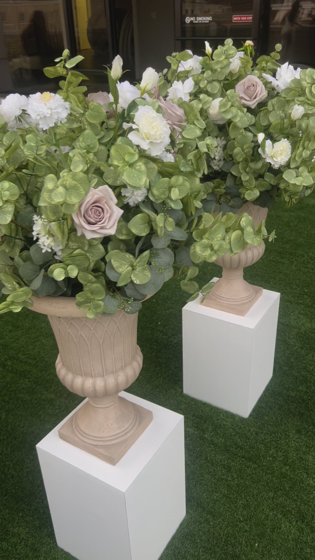 These floral urns are made with eucalyptus, taupe roses, white roses, white ranunculus, and white lisanthus. They are light and airy.